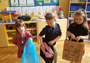 zabawa „Którą torbę zabierzemy na zakupy?” – trzy dziewczynki prezentują torby: foliową, papierową i torbę z tkaniny
